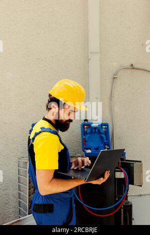 Un tecnico esperto che ordina nuovi componenti per il condizionatore d'aria difettoso dopo aver completato le riparazioni. Specialista esperto che cerca online i componenti di ricambio per sistemi hvac Foto Stock