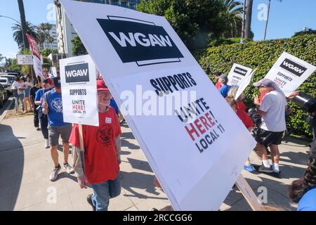 Los Angeles, California, USA. 13 luglio 2023. I membri di WGA e WGAW si uniscono QUI! Local 11 per supportare i lavoratori dell'hotel che fanno picchetti fuori dal Fairmont Miramar Hotel & Bungalows a Santa Monica, California, 13 luglio 2023. (Immagine di credito: © Ringo Chiu/ZUMA Press Wire) SOLO USO EDITORIALE! Non per USO commerciale! Foto Stock