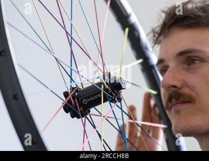 13 luglio 2023, Sassonia, Chemnitz: Erik Fickelscheer controlla una ruota con razze tessili in produzione presso la fabbrica Pi Rope di Chemnitz. Al posto dell'acciaio, la manifattura di razze e ruote produce razze Vectran, un poliestere ad alta resistenza. Ciò rende le ruote delle biciclette particolarmente leggere. L'industria ciclistica della Sassonia ha beneficiato del boom del settore negli ultimi anni e sta aprendo nuovi orizzonti per il futuro. Ad esempio, sono emerse nuove Start-up accanto alla tradizionale azienda Diamant. Con circa 10.000 dipendenti in più di 300 aziende, il settore in Sassonia genera Foto Stock