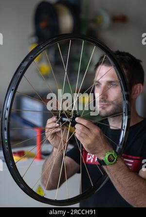 13 luglio 2023, Sassonia, Chemnitz: David Wegehaupt controlla una ruota con razze tessili in produzione presso la Pi Rope Factory di Chemnitz. Al posto dell'acciaio, la manifattura di razze e ruote produce razze Vectran, un poliestere ad alta resistenza. Ciò rende le ruote delle biciclette particolarmente leggere. L'industria ciclistica della Sassonia ha beneficiato del boom del settore negli ultimi anni e sta aprendo nuovi orizzonti per il futuro. Ad esempio, sono emerse nuove Start-up accanto alla tradizionale azienda Diamant. Con circa 10.000 dipendenti in più di 300 aziende, il settore in Sassonia genera un Foto Stock