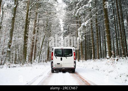 Camper Van guida su una strada attraverso una foresta coperta di neve in inverno, vacanza avventura e stile di vita nei boschi, Germania Foto Stock