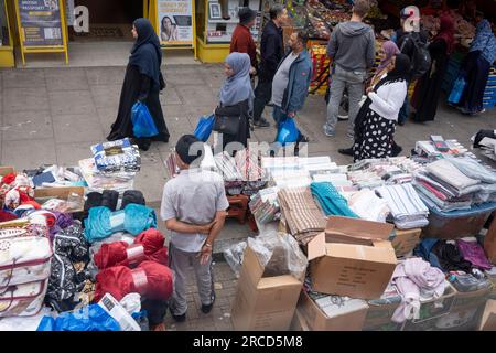 Le donne che fanno shopping camminano davanti a un mercato di strada a Bethnal Green, il 13 luglio 2023, a Londra, in Inghilterra. Foto Stock