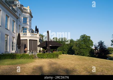 Arnhem, Paesi Bassi - 11 giugno 2023: Il retro della villa bianca Sonsbeek con terrazza e un prato verde e giallo con un cielo azzurro Foto Stock