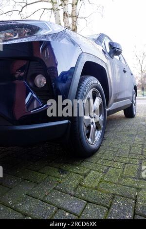 Brecht, Belgio - 21 gennaio 2022: Un ritratto del faro destro di un'auto ibrida toyota rav4 blu scuro parcheggiata su un vialetto. Il veicolo è in grado di guidare Foto Stock