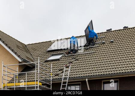 Barendrecht, Paesi Bassi - 2020-12-03: Due tecnici installano pannelli fotovoltaici sul tetto di una casa Foto Stock