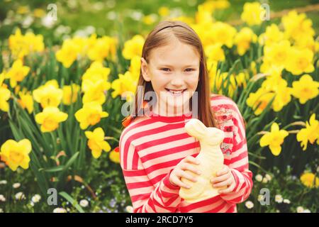 Simpatica bambina con coniglio pasquale di cioccolato bianco che celebra la festa tradizionale. Famiglia, vacanza, primavera, concetto di infanzia spensierata. Foto Stock