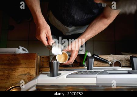 Dettaglio della vista dall'alto dell'uomo caucasico che versa latte in una tazza di caffè Foto Stock