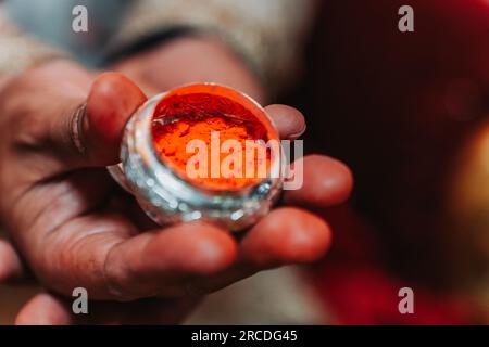 La mano di The Groom che tiene sindur o Vermiglio prima di applicare sulla separazione dei capelli della sposa.fuoco selettivo Foto Stock