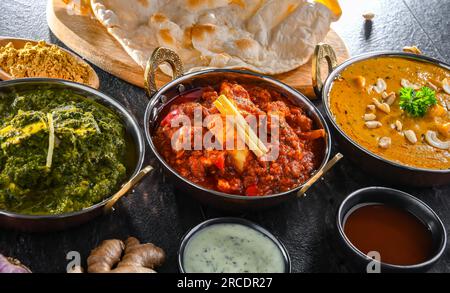 Composizione con piatti indiani: Paneer di madras, paneer di palak e paneer di shahi con riso basmati servito in pentole originali di karahi indiani. Foto Stock