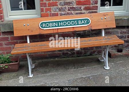 Panchina a Robin Hoods Bay, con vecchio cartello della stazione ferroviaria in ghisa, vicino a Whitby, North Yorkshire, Inghilterra, Regno Unito, YO22 4SE Foto Stock