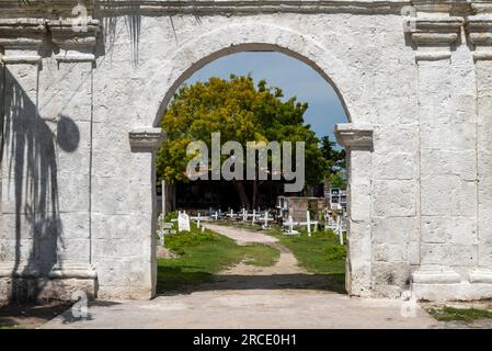 Grande struttura ad arco, costruita in pietra bianca, che conduce ad un albero, e l'area principale di molte tombe a camera e crocifissi bianchi che segnano le centinaia Foto Stock