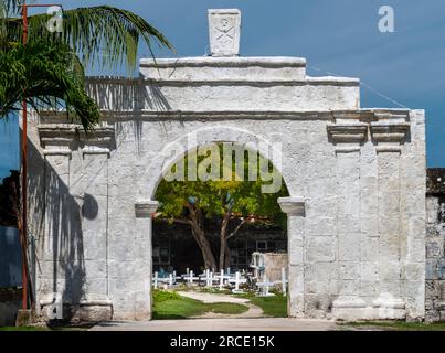 Grande struttura ad arco, costruita in pietra bianca, che conduce ad un albero, e l'area principale di molte tombe a camera e crocifissi bianchi che segnano le centinaia Foto Stock