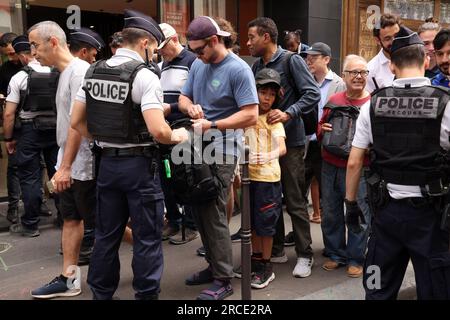 Parigi, Francia. 14 luglio 2023. La gente viene perquisita dalle forze di sicurezza prima di entrare negli Champs Elysees Avenue per partecipare alla parata militare del giorno della Bastiglia a Parigi, in Francia, venerdì 14 luglio 2023. La Francia ha intensificato le misure di sicurezza per le celebrazioni annuali del paese dopo che il paese è stato colpito da rivolte. Foto di Maya Vidon-White/UPI credito: UPI/Alamy Live News Foto Stock