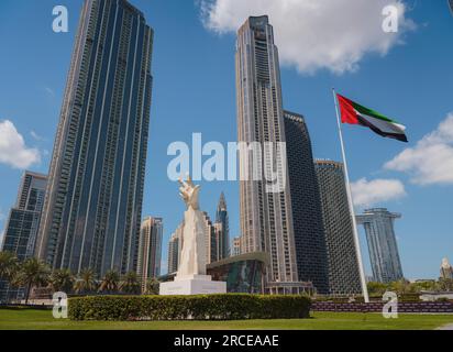 20 marzo 2023, Dubai, Emirati Arabi Uniti: Statua a tre dita vicino alla bandiera degli Emirati Arabi Uniti nei giorni di sole e Burj Khalifa, conosciuto come il grattacielo più alto del mondo. E' conosciuto per essere l'edificio piu' alto del mondo. Foto Stock