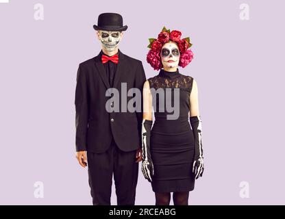 Zombie Lovestory. Coppia in maschera il giorno dei costumi funebri morti in piedi l'uno accanto all'altro Foto Stock