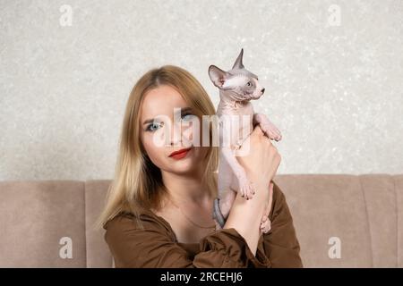 Una donna tiene in mano un piccolo gattino canadese Sphynx. Amore per gli animali domestici, giorno del gatto. Foto Stock