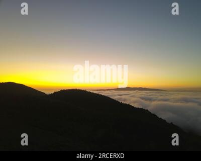 Tramonto sulle montagne sopra le nuvole nel lago del fuoco Lagoa do Fogo sull'isola di São Miguel nelle Azzorre. Foto Stock