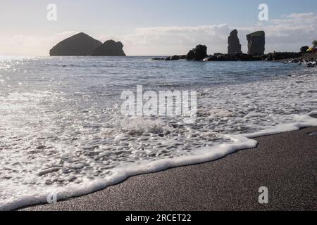 Spiaggia di sabbia nera a Mosteiros, con le grandi scogliere sullo sfondo. Isola di Sao Miguel nelle Azzorre Foto Stock