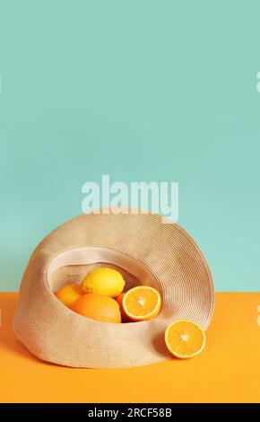 Arance succose mature e limone in un cappello estivo. Composizione estiva della raccolta degli agrumi. Foto brillante per lo striscione estivo, minimalismo. I cibi sono molto buoni Foto Stock