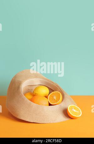 Arance succose mature e limone in un cappello estivo. Composizione estiva della raccolta degli agrumi. Foto brillante per lo striscione estivo, minimalismo. I cibi sono molto buoni Foto Stock