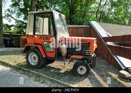 Trattore compatto rosso Agria 590 nel cortile di una casa di campagna. Soleggiato giorno d'estate. Vista laterale. Marianske Lazne, Repubblica Ceca - 10 luglio 2023. Foto Stock