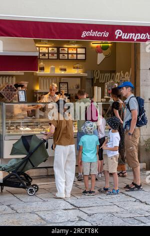 famiglia giovane in vacanza che acquista gelati, famiglia con bambini piccoli che aspetta alla gelateria, famiglia che acquista gelati dal negozio. Foto Stock