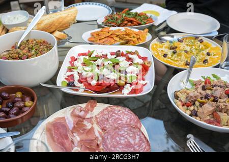 Tavolo estivo con insalate, spuntini e pane per una festa con amici o familiari, attenzione selezionata, profondità di campo ristretta Foto Stock
