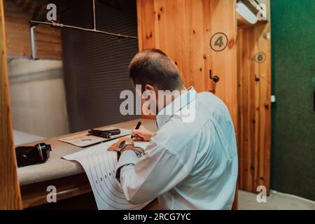 Un uomo in un poligono scatta una foto ed esamina i risultati dopo la ripresa Foto Stock