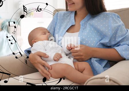 Madre che canta ninnananna al suo bambino a casa. Illustrazione di note musicali volanti intorno a donna e bambino Foto Stock