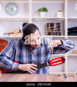 Il giovane bello repairman riparazione di chitarra Foto Stock