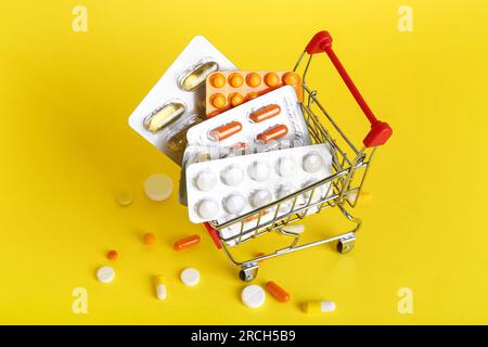 Mini carrello con diversi farmaci su sfondo giallo Foto Stock