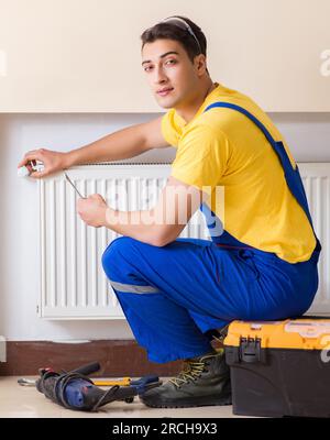 Il giovane imprenditore repairman riparazione pannello di riscaldamento Foto Stock