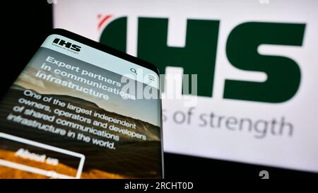 Telefono cellulare con pagina Web della società di telecomunicazioni IHS Holding Limited sullo schermo davanti al logo. Concentrarsi sul centro del display del telefono. Foto Stock