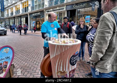 Promozione caffè con assaggi gratuiti consegnati ai passanti presso New Street, Birmingham, Inghilterra, Regno Unito Foto Stock