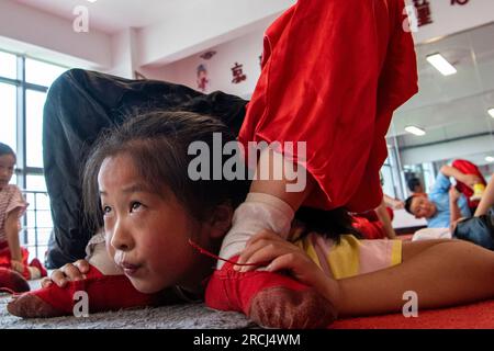 HAI'AN, CINA - 15 LUGLIO 2023 - i bambini di una scuola elementare club dell'Opera di Pechino praticano le abilità di base dello spettacolo dell'Opera di Pechino sotto la guida Foto Stock