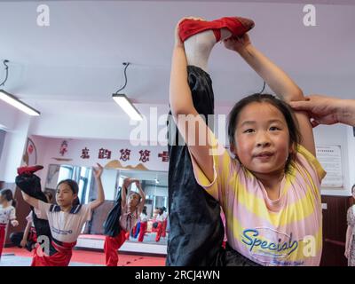 HAI'AN, CINA - 15 LUGLIO 2023 - i bambini di una scuola elementare club dell'Opera di Pechino praticano le abilità di base dello spettacolo dell'Opera di Pechino sotto la guida Foto Stock