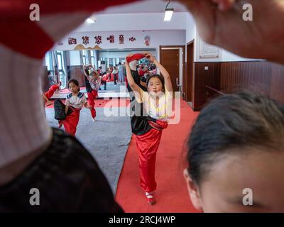 HAI'AN, CINA - 15 LUGLIO 2023 - i bambini di una scuola elementare club dell'Opera di Pechino praticano le abilità di base dello spettacolo dell'Opera di Pechino sotto la guida Foto Stock