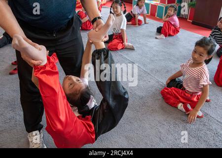 HAI'AN, CINA - 15 LUGLIO 2023 - i bambini di una scuola elementare club dell'Opera di Pechino praticano le abilità di base dello spettacolo dell'Opera di Pechino sotto la guida Foto Stock