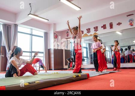 HAI'AN, CINA - 15 LUGLIO 2023 - i bambini di una scuola elementare club dell'Opera di Pechino praticano le abilità di base dello spettacolo dell'Opera di Pechino sotto la guida Foto Stock