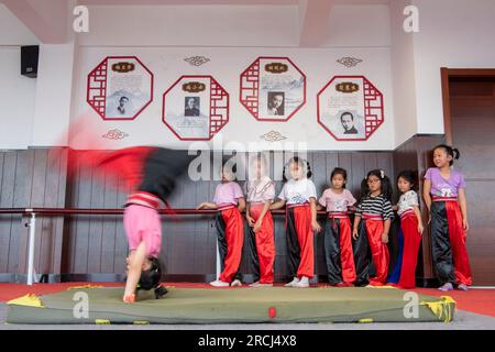 HAI'AN, CINA - 15 LUGLIO 2023 - i bambini di una scuola elementare club dell'Opera di Pechino praticano le abilità di base dello spettacolo dell'Opera di Pechino sotto la guida Foto Stock