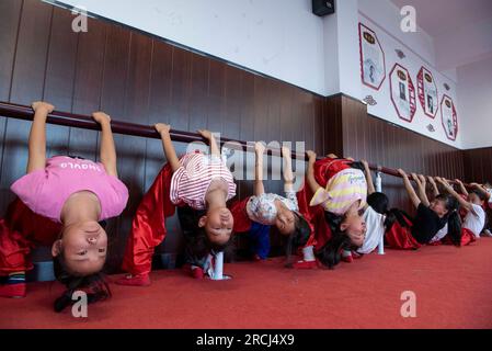 HAI'AN, CINA - 15 LUGLIO 2023 - i bambini di una scuola elementare club dell'Opera di Pechino praticano le abilità di base dello spettacolo dell'Opera di Pechino sotto la guida Foto Stock