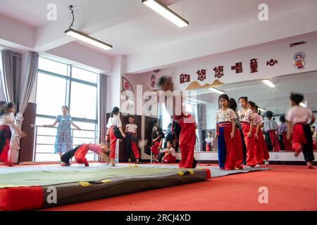 HAI'AN, CINA - 15 LUGLIO 2023 - i bambini di una scuola elementare club dell'Opera di Pechino praticano le abilità di base dello spettacolo dell'Opera di Pechino sotto la guida Foto Stock