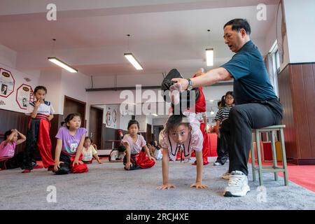 HAI'AN, CINA - 15 LUGLIO 2023 - i bambini di una scuola elementare club dell'Opera di Pechino praticano le abilità di base dello spettacolo dell'Opera di Pechino sotto la guida Foto Stock