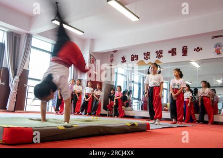 HAI'AN, CINA - 15 LUGLIO 2023 - i bambini di una scuola elementare club dell'Opera di Pechino praticano le abilità di base dello spettacolo dell'Opera di Pechino sotto la guida Foto Stock