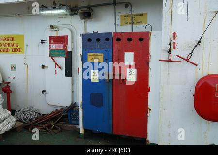 Stoccaggio di bombole di ossigeno e di acetilene dietro le porte di metallo blu e rosso con adesivi di avvertenza situati sulla nave. Foto Stock