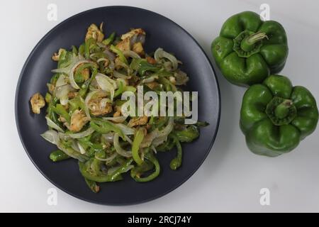 Mescolare il peperone fritto e il pollo su un piatto nero. Mescolare il pollo fritto con peperoni saltati e cipolle nell'olio d'oliva. Un piatto salutare con pollo Foto Stock