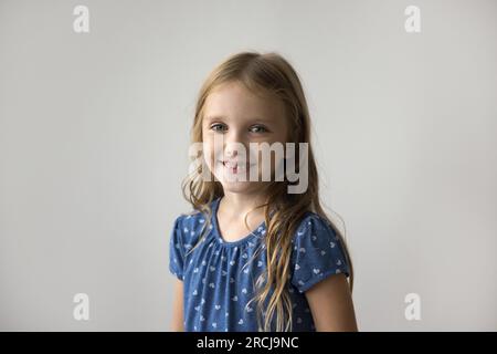 Felice, affascinante e adorabile bambina in piedi al muro bianco Foto Stock