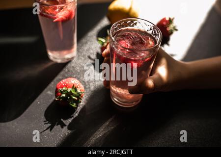 Delizia alla fragola. Una bevanda estiva dolce e piccante servita in un bicchiere con cubetti di ghiaccio. colore rosa e fette di fragola fresca Foto Stock