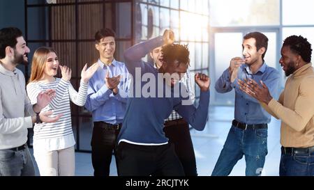 i dipendenti dei millennial entusiasti e felici gridano di gioia, alzando le mani per gli eccitati pugni. Foto Stock