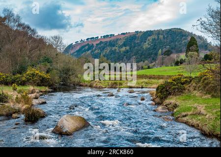 Il fiume scorre con St. Kevin's Kitchen in the background, Glendalough, County Wicklow, Repubblica d'Irlanda Foto Stock